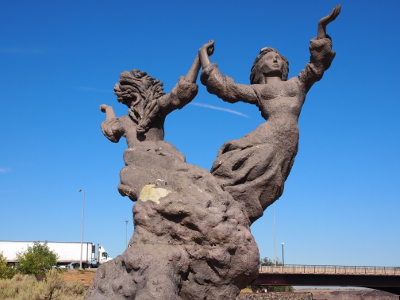 [Along the rim trail is a statue of two women holding an arm back to hold the hand of the other as they face opposite directions.]